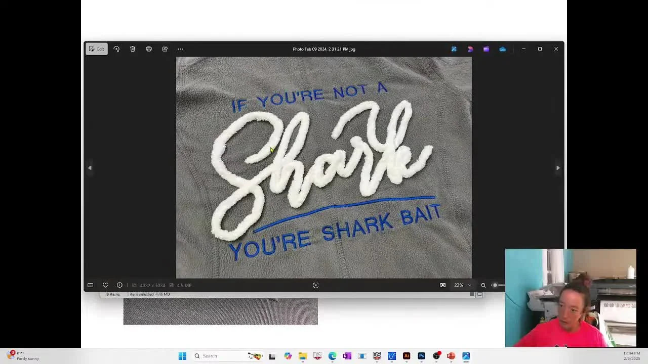 A close-up of a finished script-style chenille yarn couching embroidery reading “Shark,” showing clean tack-down stitches and a bold raised yarn line.