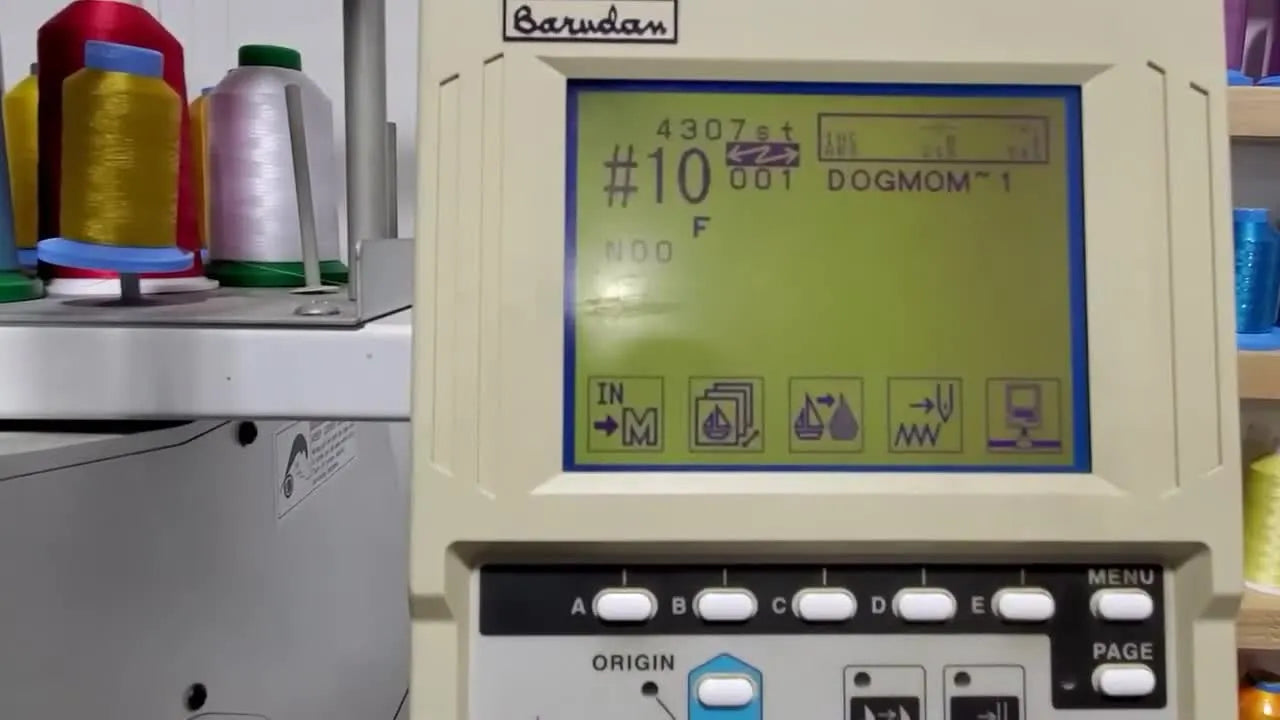 A close-up of an operator’s fingers using the Barudan control panel keys to navigate design transfer and color programming menus.