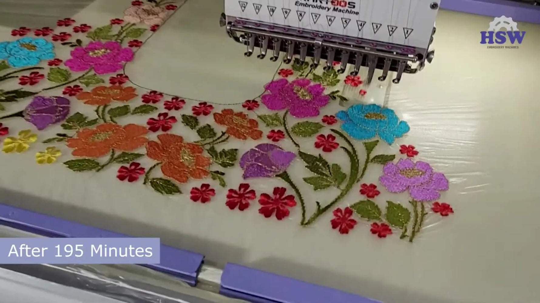 A close-up view of a vibrant floral design being stitched onto sheer net fabric, showing clean edges and metallic thread shine.