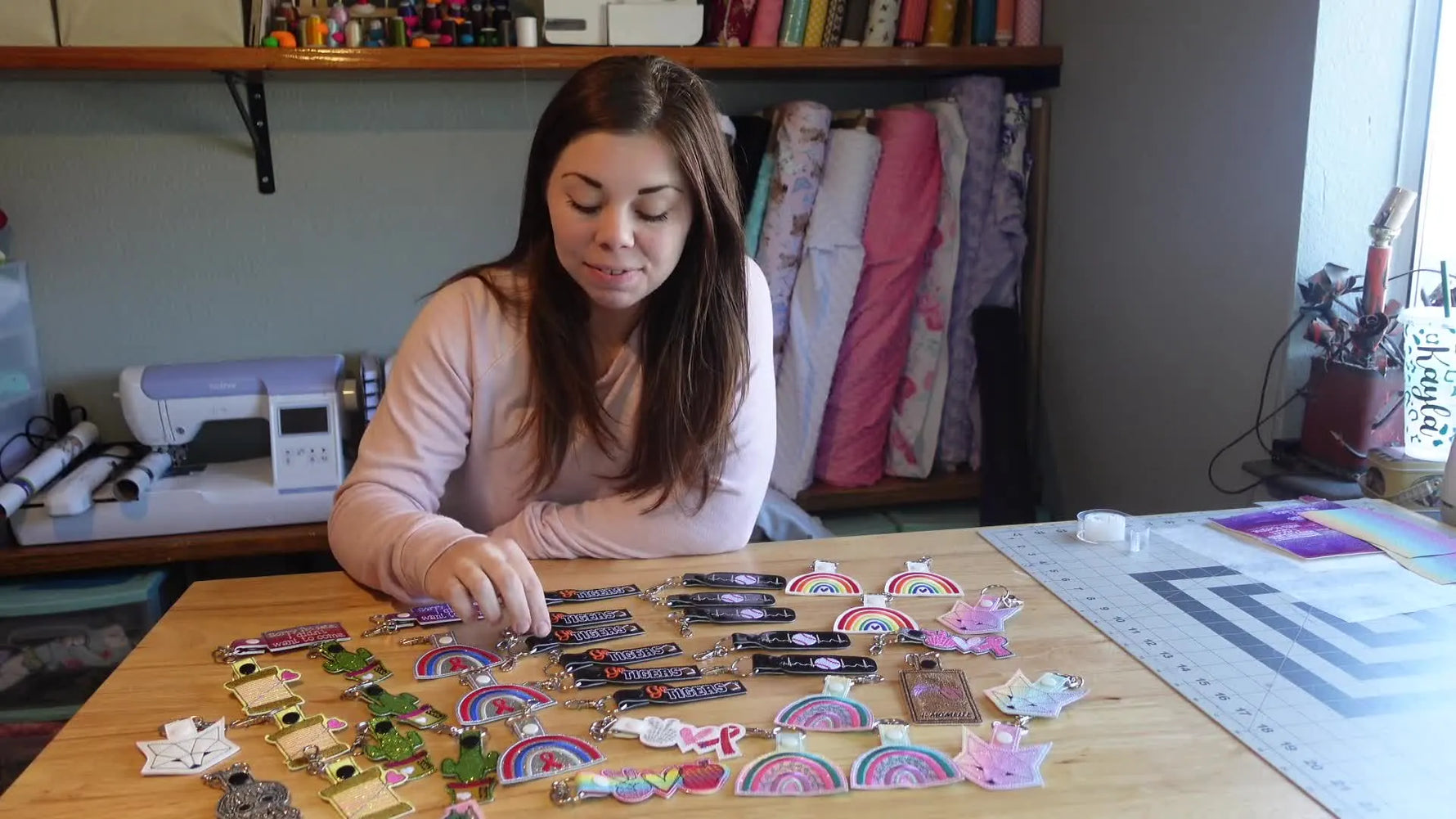 Woman holding up a snap tab keychain, with many other keychains on the table.