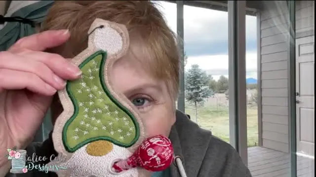 A close-up of the finished ITH gnome ornament holding a lollipop, showing the stitched beard texture and the clean punched opening.