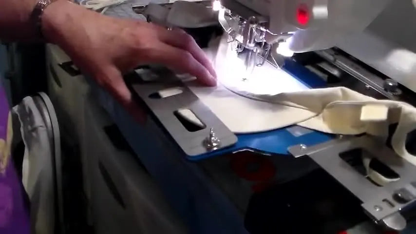 A close-up of a multi-needle embroidery machine stitching a small logo onto a visor bill at speed.