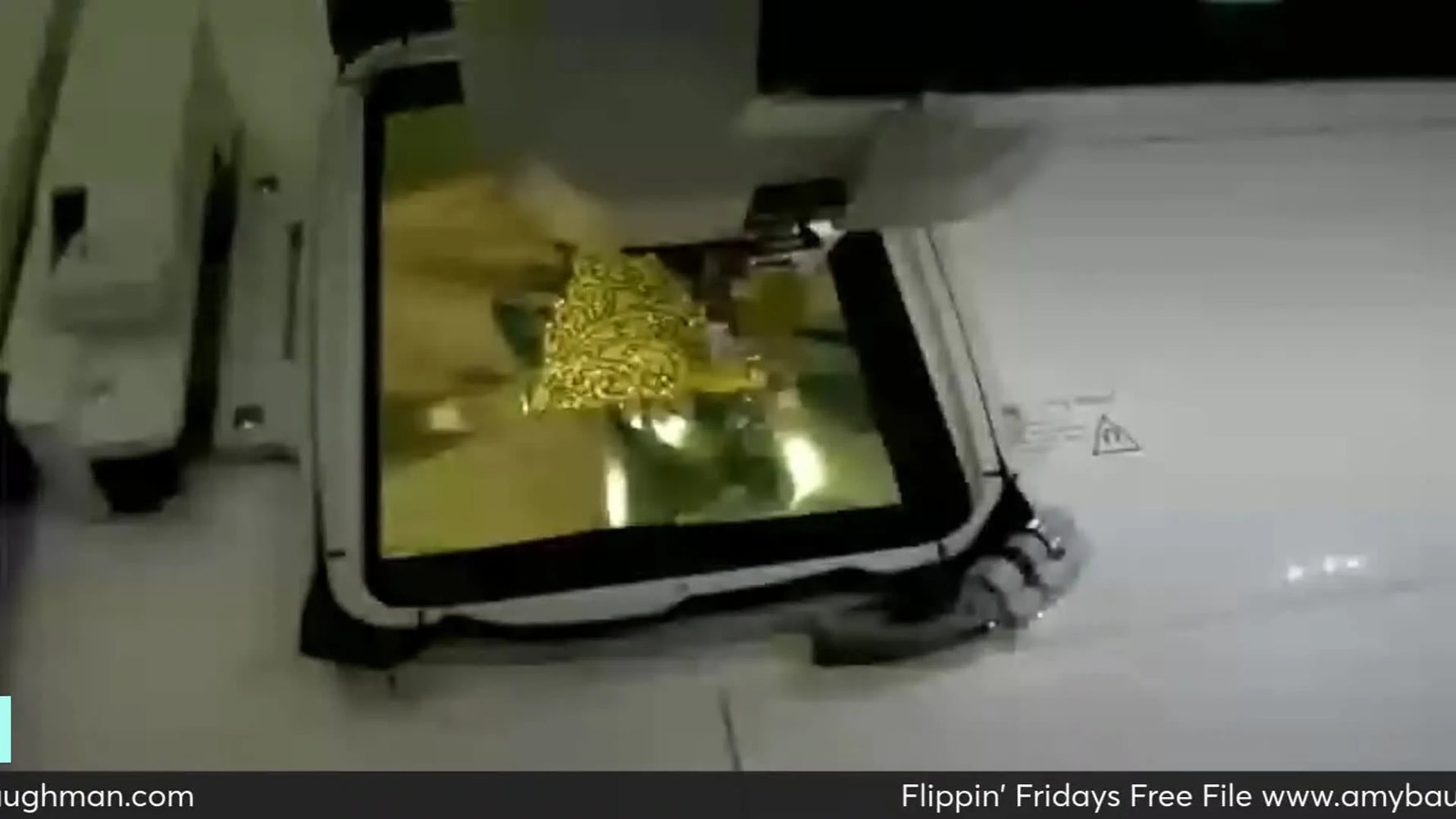 Close-up of an embroidery machine stitching intricate gold thread onto gold Mylar film, forming a Christmas tree design.