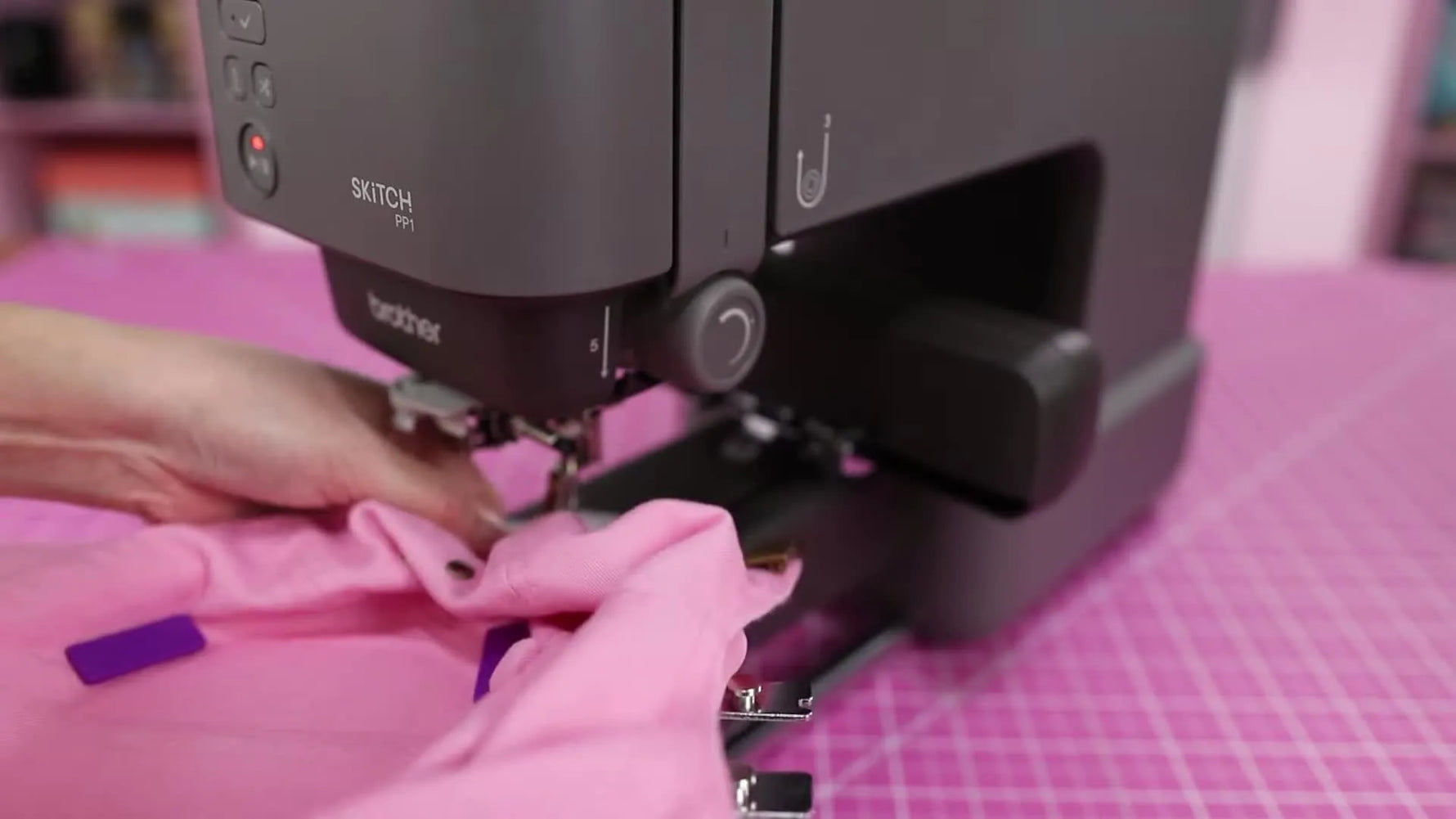 Side view of the Brother Skitch PP1 with an unstructured cap loaded in the magnetic hoop while small magnets hold the sweatband safely out of the stitch path.