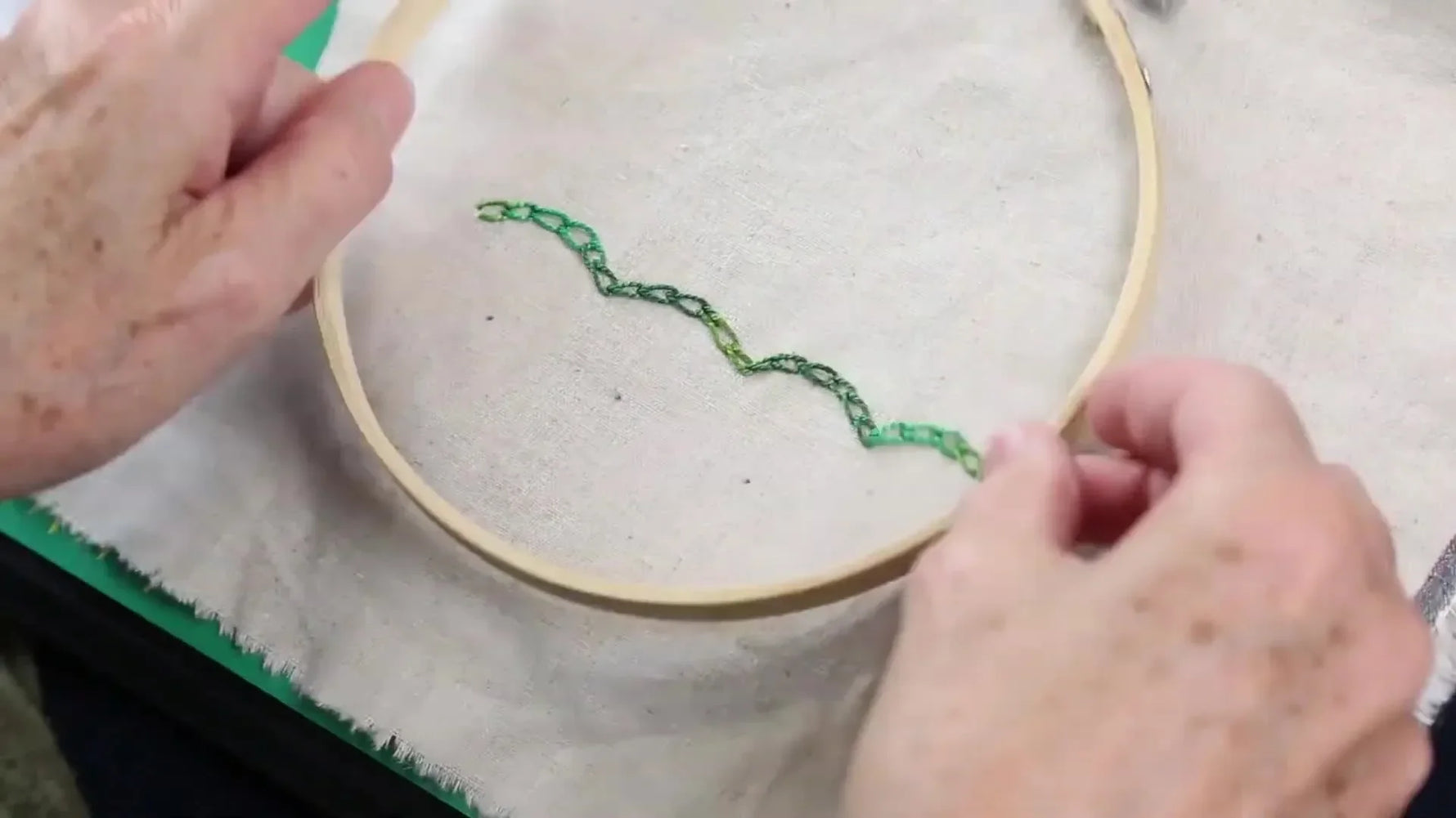Hands gently pressing fabric into an embroidery hoop, securing it for stitching.