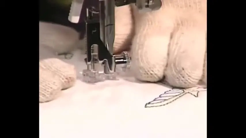 Close-up of gloved hands guiding fabric under the needle while stitching controlled free-motion stippling.