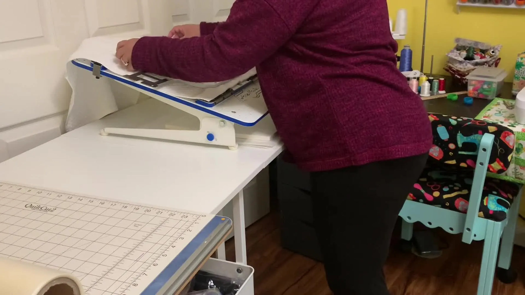 A kitchen towel is being secured in a magnetic hoop on a hooping station as the top frame snaps down over the towel-and-stabilizer sandwich.