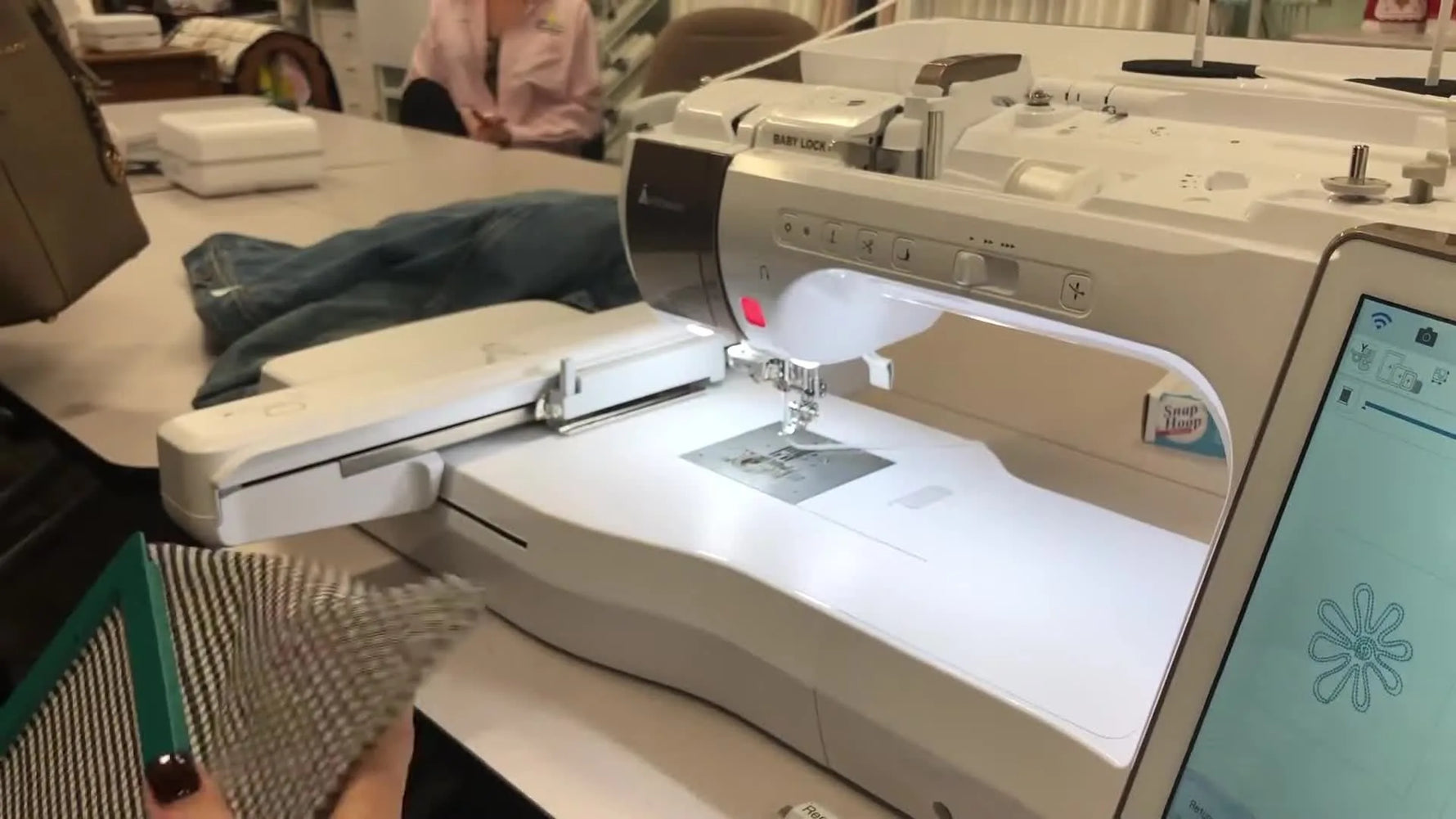 A Baby Lock Solaris stitches a floral couching design while a magnetic hoop holds gingham fabric steady on the embroidery arm.