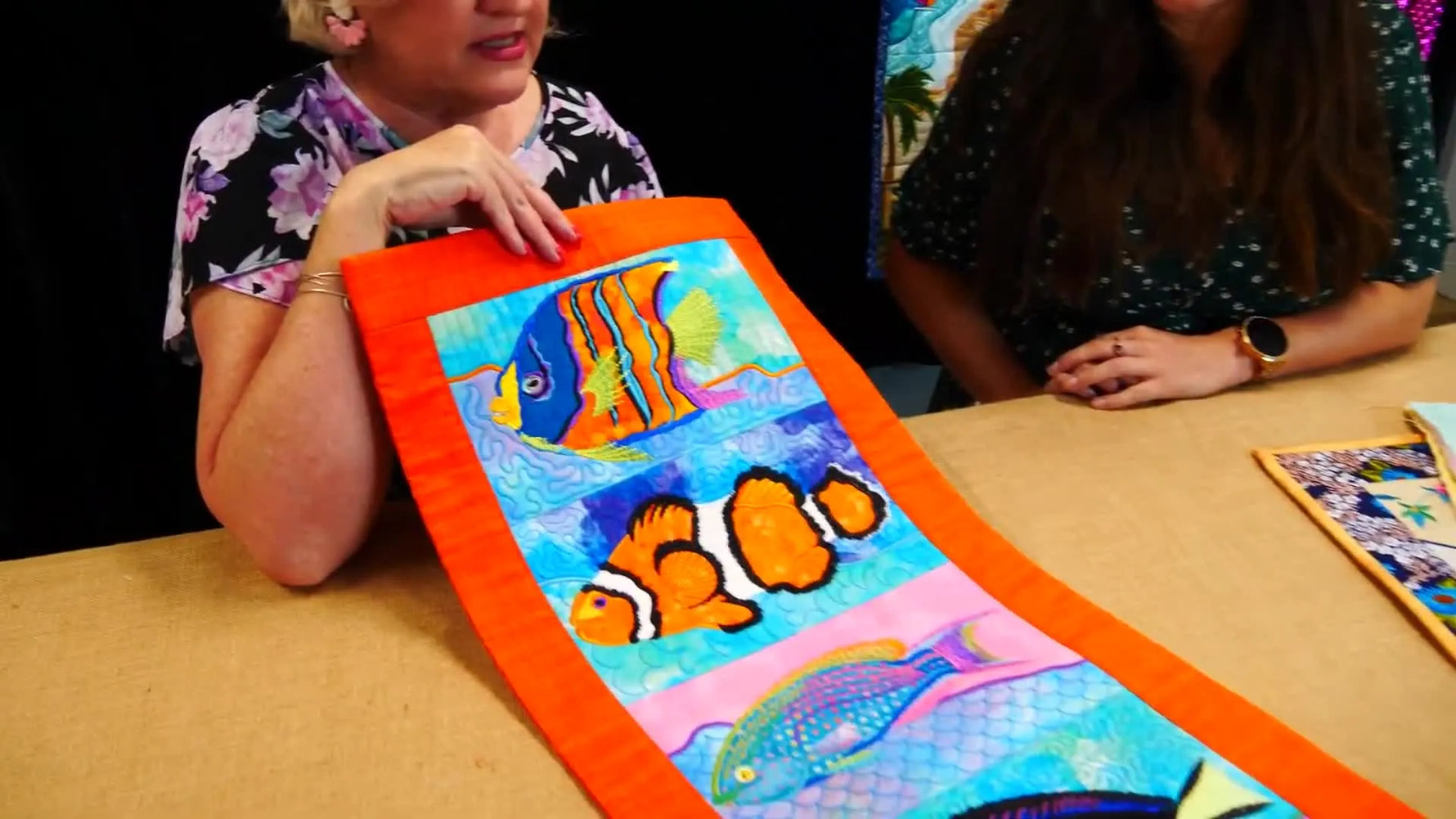 A bright Tropical Fish table runner stitched on orange batik fabric, showing vivid threadwork and clean ITH construction.