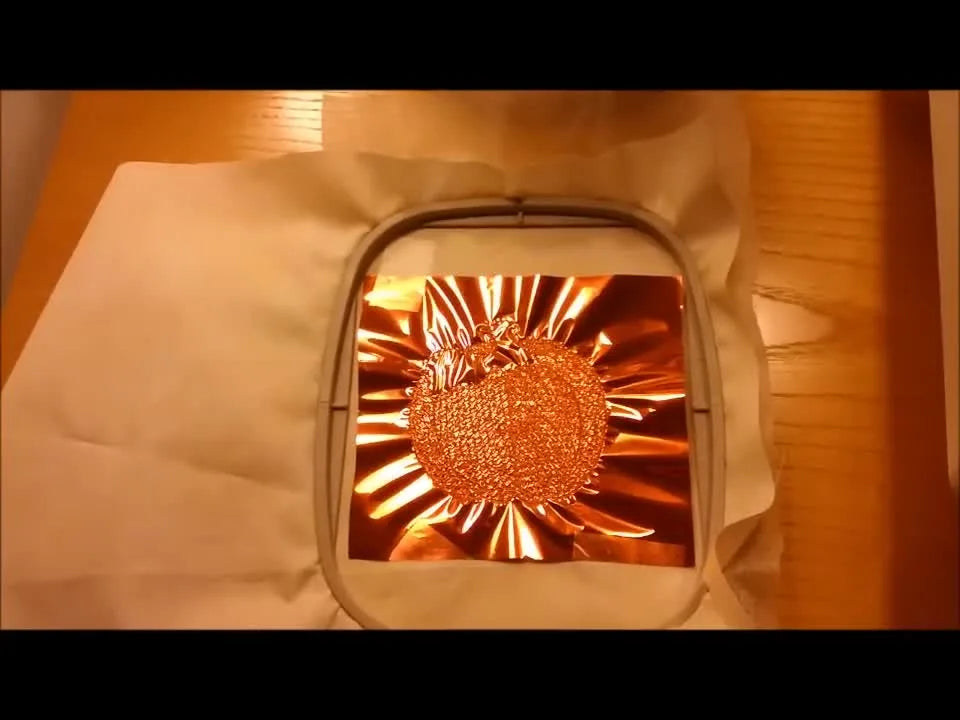 A close-up view of the pumpkin fill stitched over Mylar, showing the perforation line that will allow a clean tear-away edge.