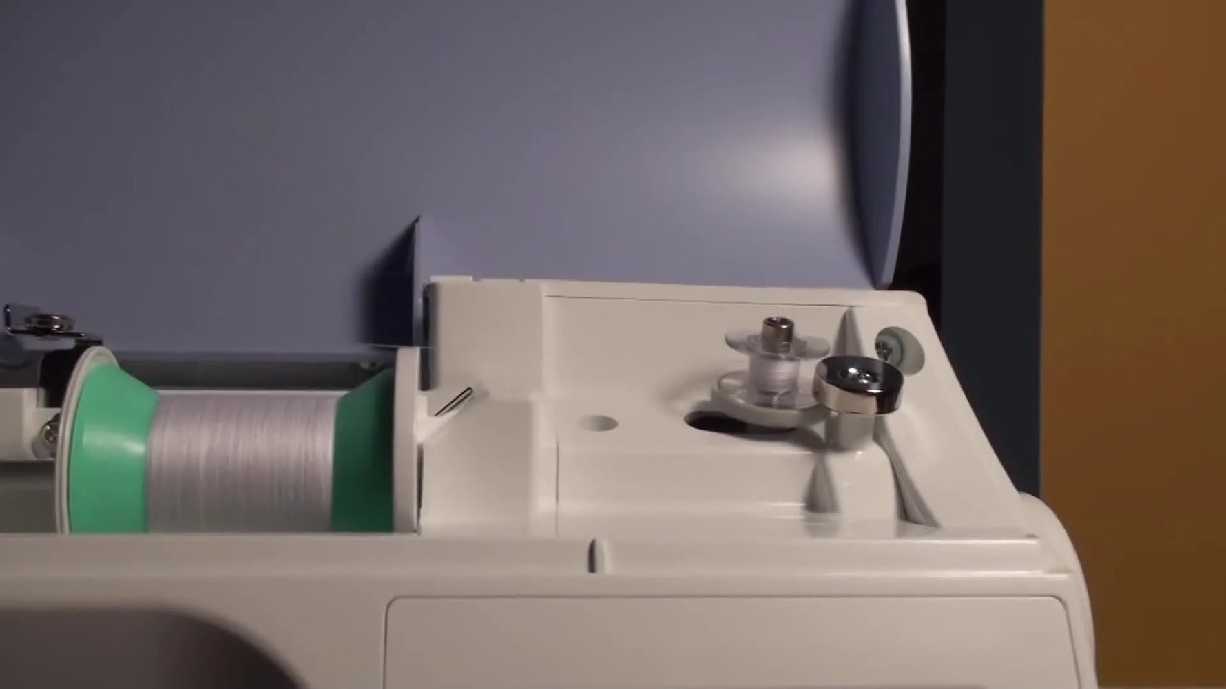 A close-up of the Brother PE 770 bobbin winder spinning a bobbin smoothly as it fills with white 90wt bobbin thread.