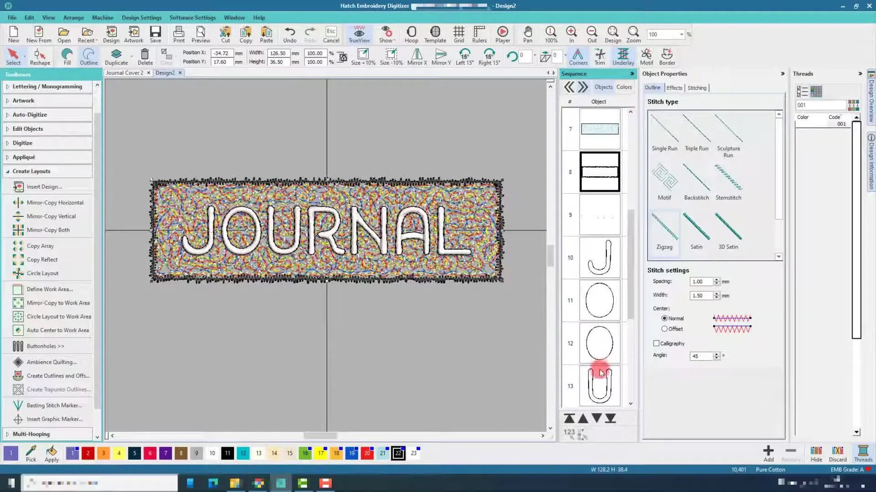 A finished multi-colored stipple texture block with the word JOURNAL stitched in white and outlined in black, shown in the hoop on white fabric.
