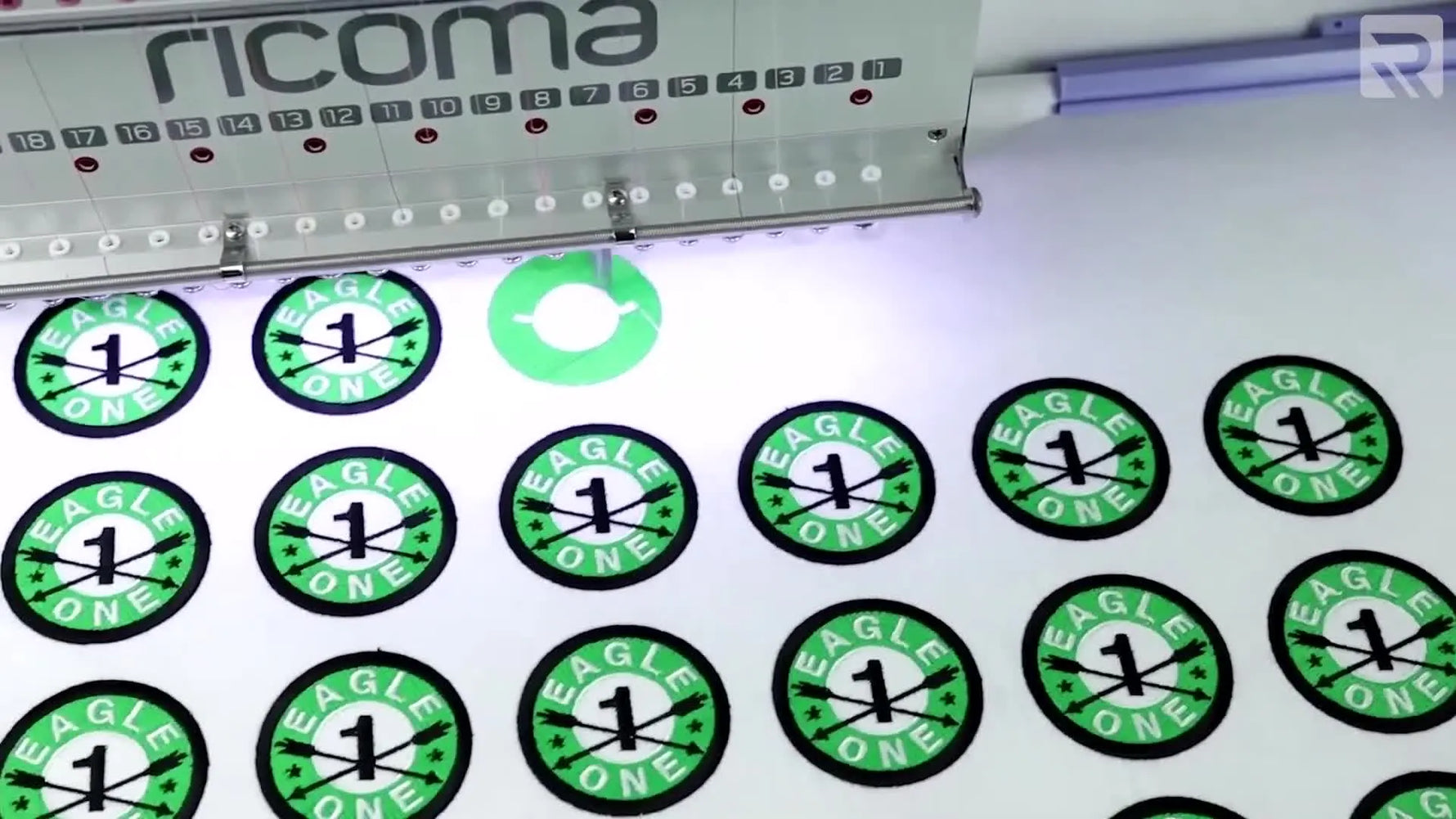 An overhead view of a large flat embroidery frame running multiple patch designs at once, showing how field size drives production efficiency.