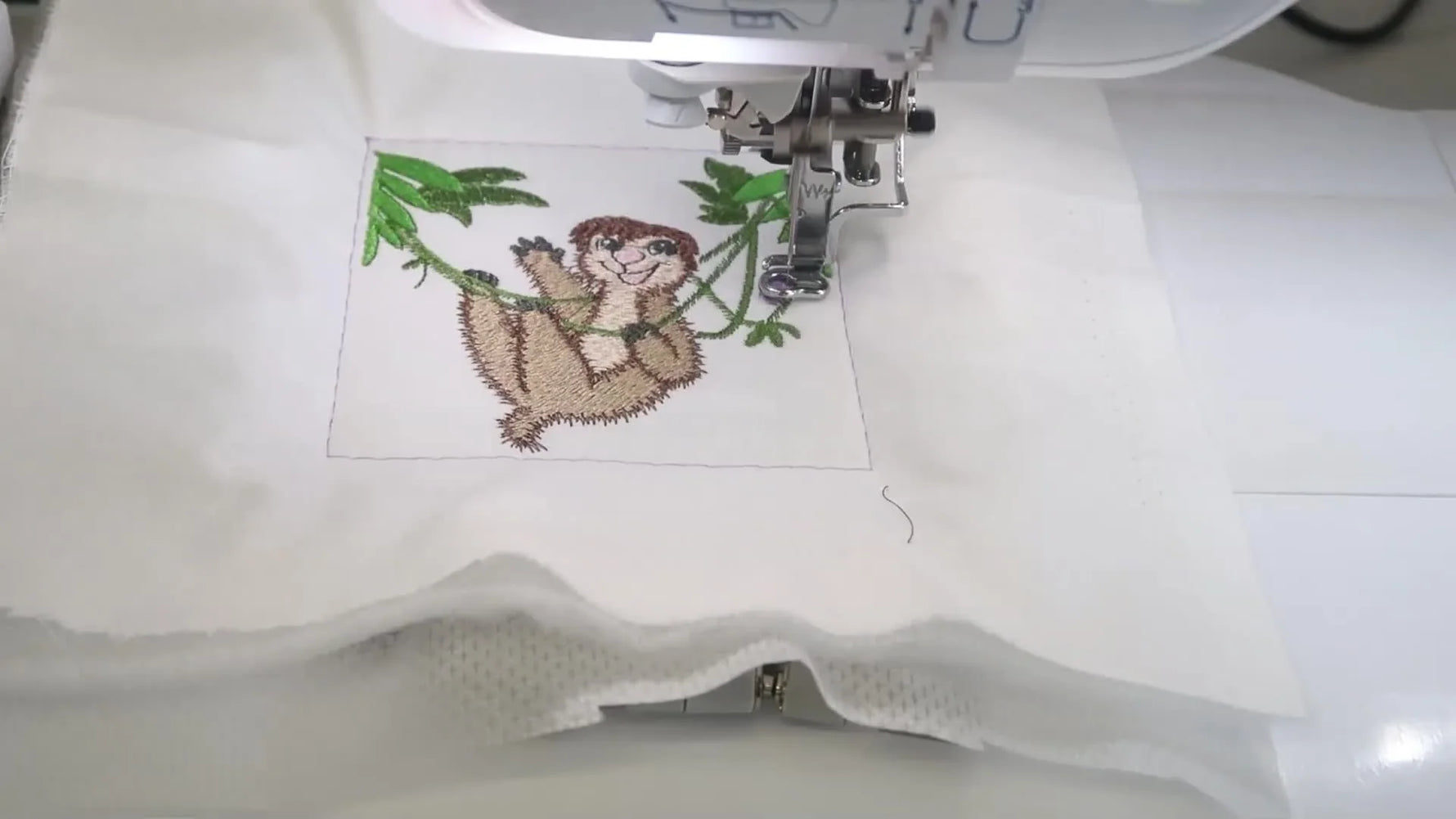 A close-up of a design stitching cleanly inside a basting box, showing how temporary basting stabilizes and aligns the work before the real embroidery begins.