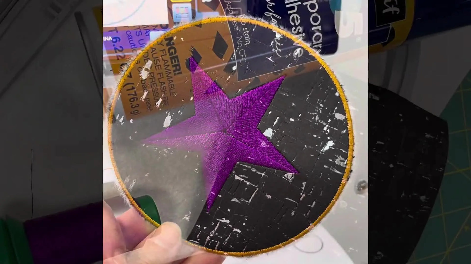 A close-up of the finished cork coaster with a purple nautical star and a gold satin-stitched border.