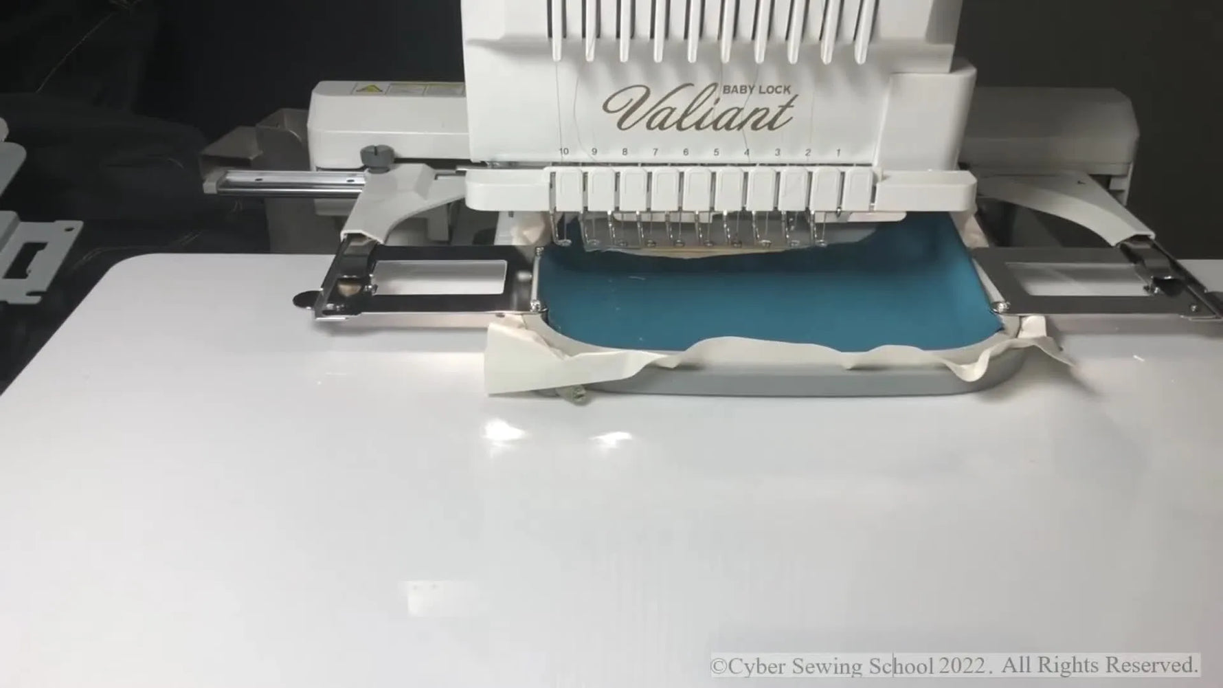 A close-up of the Baby Lock Valiant stitching a white satin keyhole buttonhole on blue denim.
