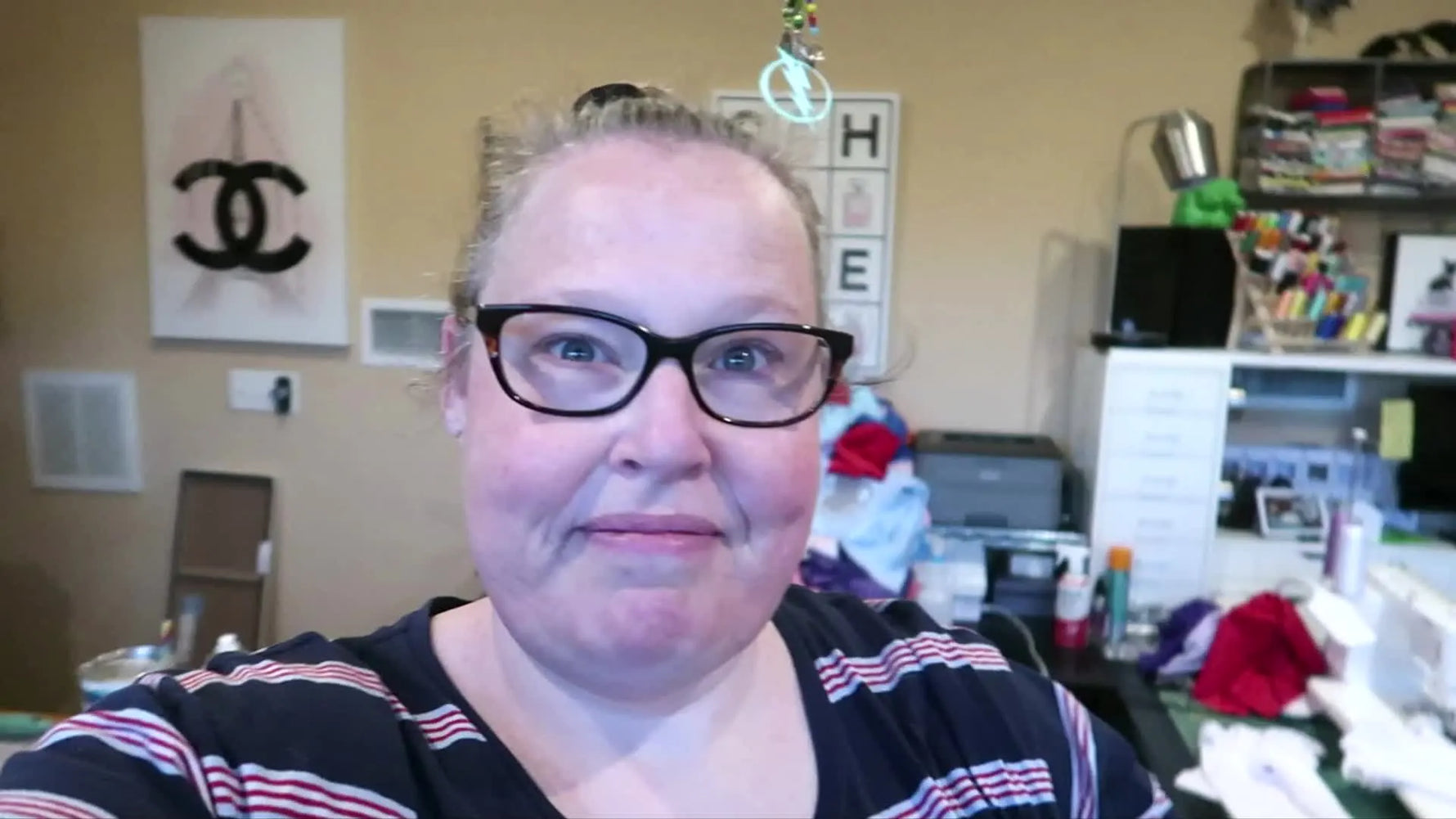 Woman smiling and greeting the camera in her craft room.