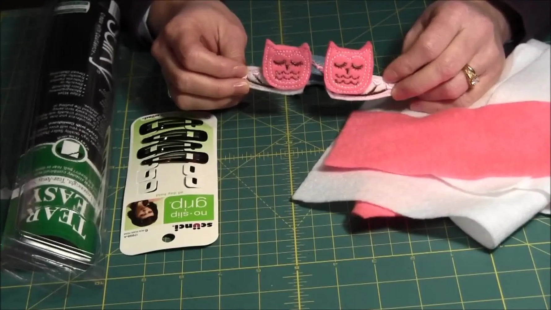 A close-up of finished pink felt owl hair clips, showing the completed ITH embroidery and snap-clip assembly.