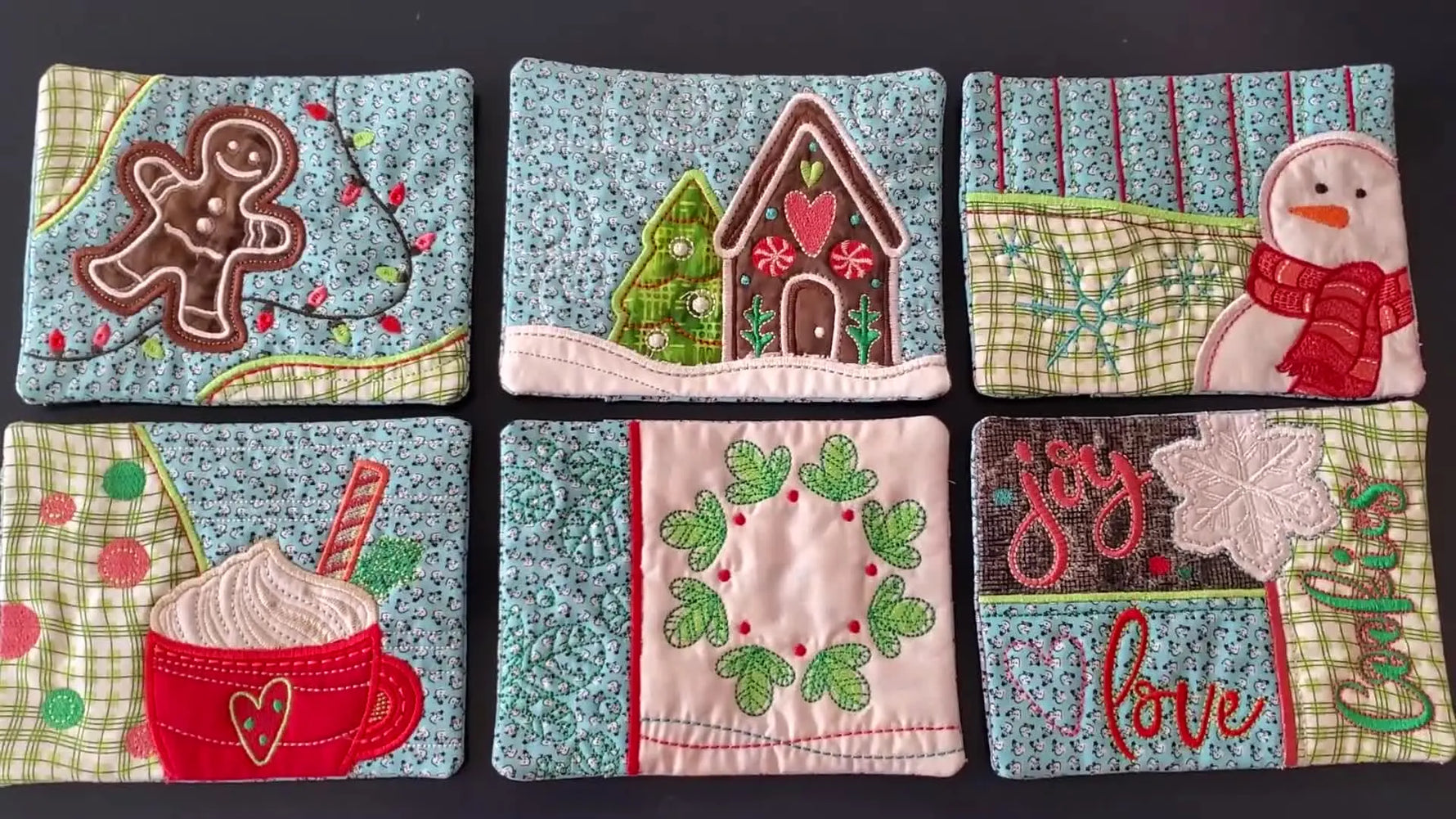 An overhead flat lay shows a coordinated set of finished holiday-themed OESD mug rugs ready for gifting or bundling as a collection.