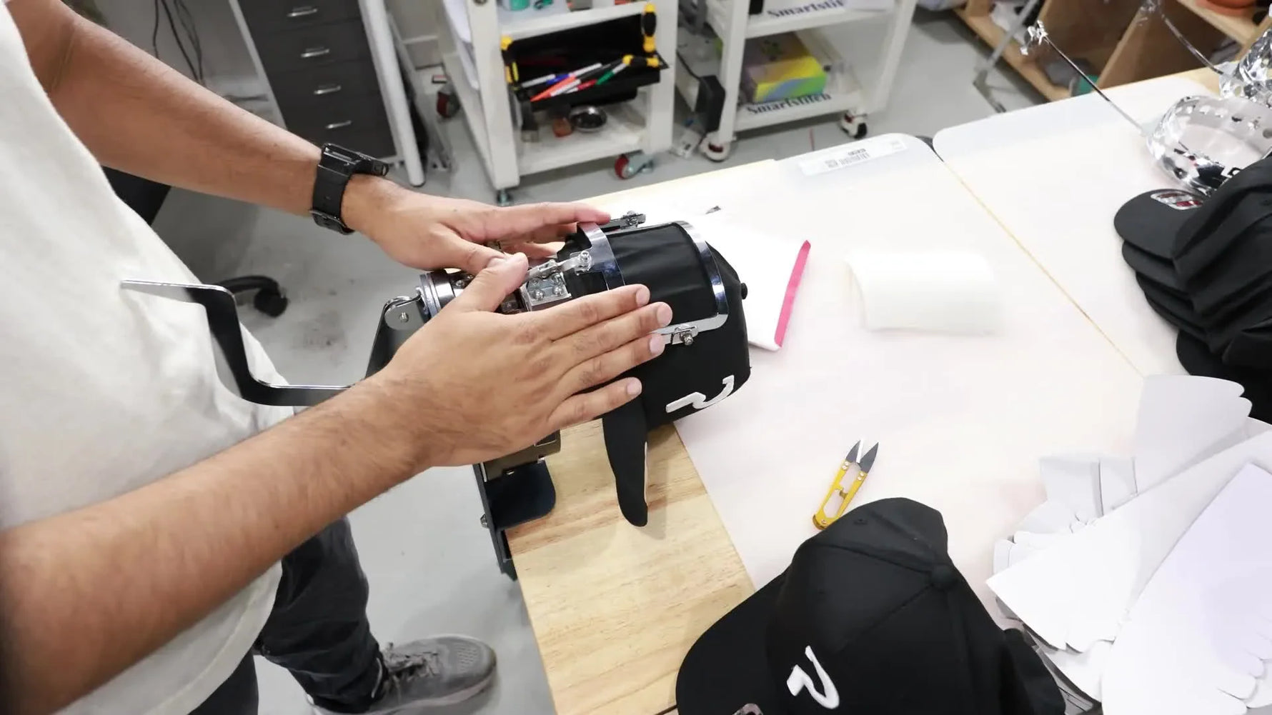 A structured black cap is clamped perfectly taut in a metal Pocket Hoop window, ready for side embroidery.