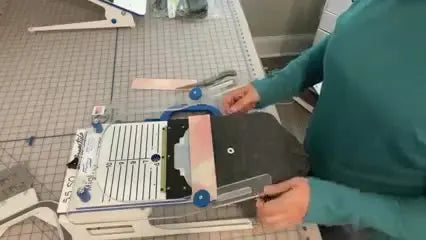 A cardboard depth template sits on the Mighty Hoop 5.5 fixture so each beanie can be slid into the exact same position without re-measuring.