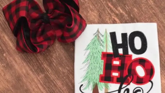 An overhead view of a finished “HO HO HO” buffalo plaid appliqué embroidery on a shirt, showing the clean edges you get when the fabric is pre-cut to the correct size.