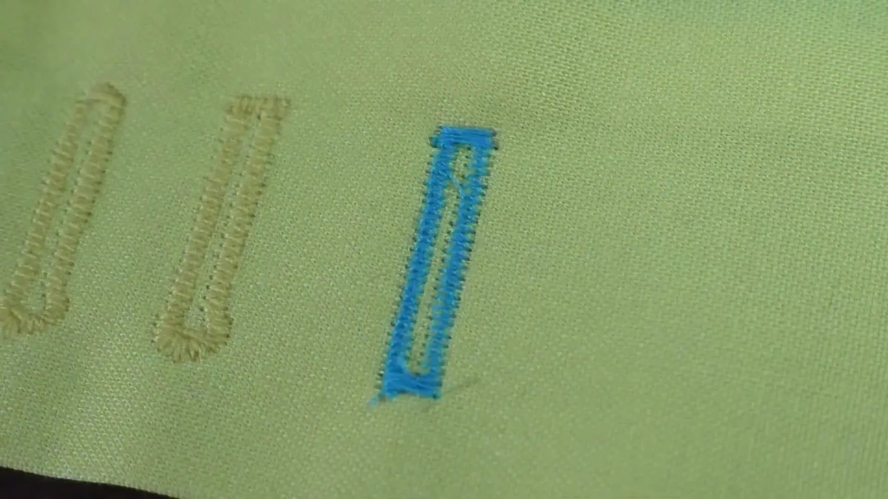 An extreme close-up of a clean, finished buttonhole stitched in contrasting thread on yellow fabric.