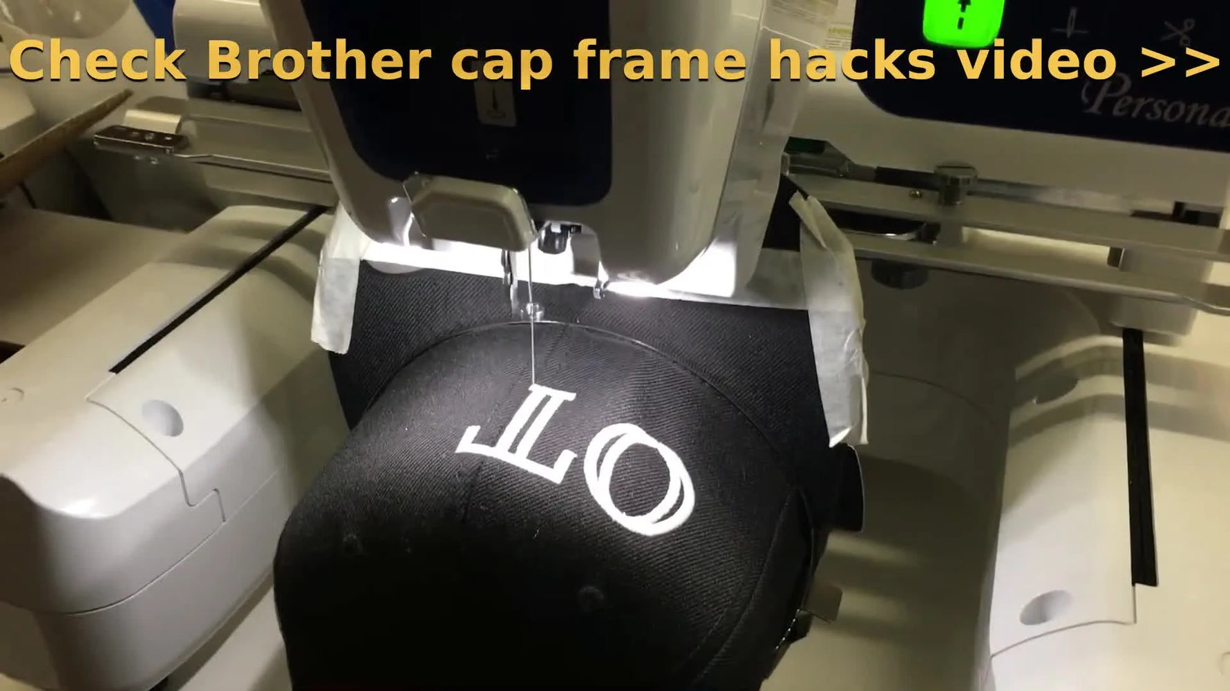 The Brother PRS100 Persona stitches white lettering onto a black cap while the wide cap frame rotates on the cylindrical arm.