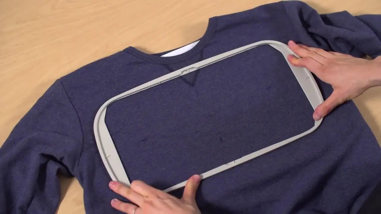 A close overhead view of a sweatshirt being hooped with alignment marks clearly matched to the hoop’s molding guides.