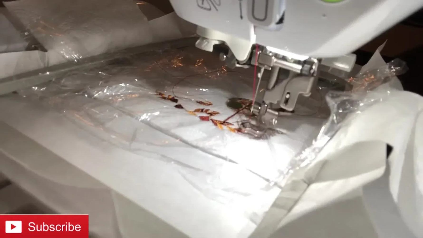 Embroidery machine stitching an autumn design with cellophane wrap on top.
