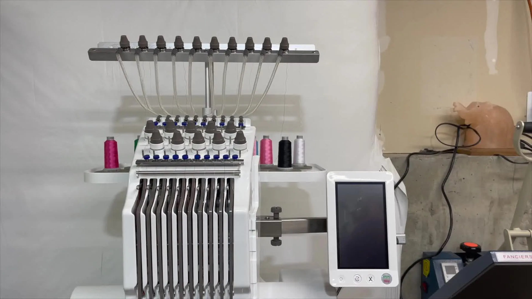 A wide shot of the Ricoma EM1010 on its sturdy stand with the touchscreen and thread tree visible, ready for multi-color production.