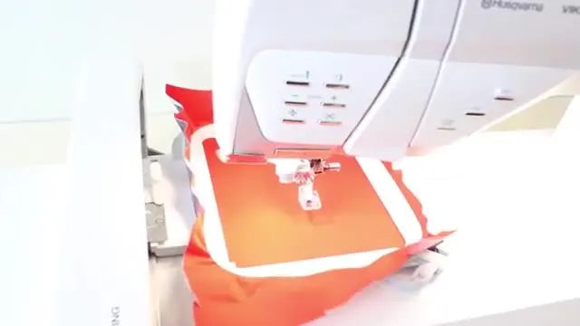 A close-up of the Designer EPIC stitching the orange outline of the pizza patch in the hoop.
