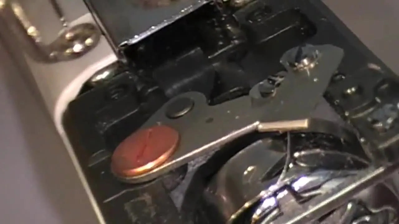 A macro close-up of the thread cutting knife mechanism inside the Brother PR bobbin arm where lint commonly packs in and causes jams.