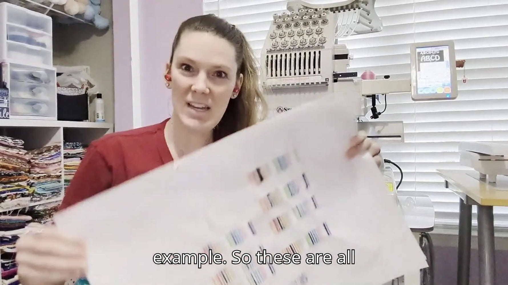 Mel holds up a stabilizer sheet filled with tension-test columns, showing how repeated swatches dial in a multi-needle machine.