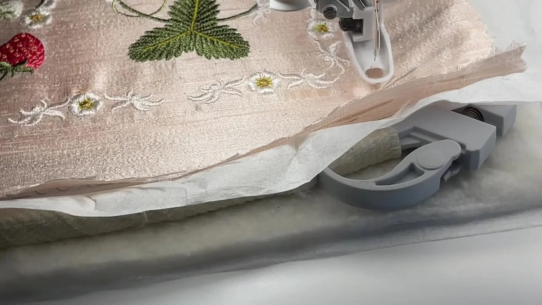 An overhead view of a quilt block in the hoop showing visible distortion lines where dense stitching has pulled the fabric inward at the sides.