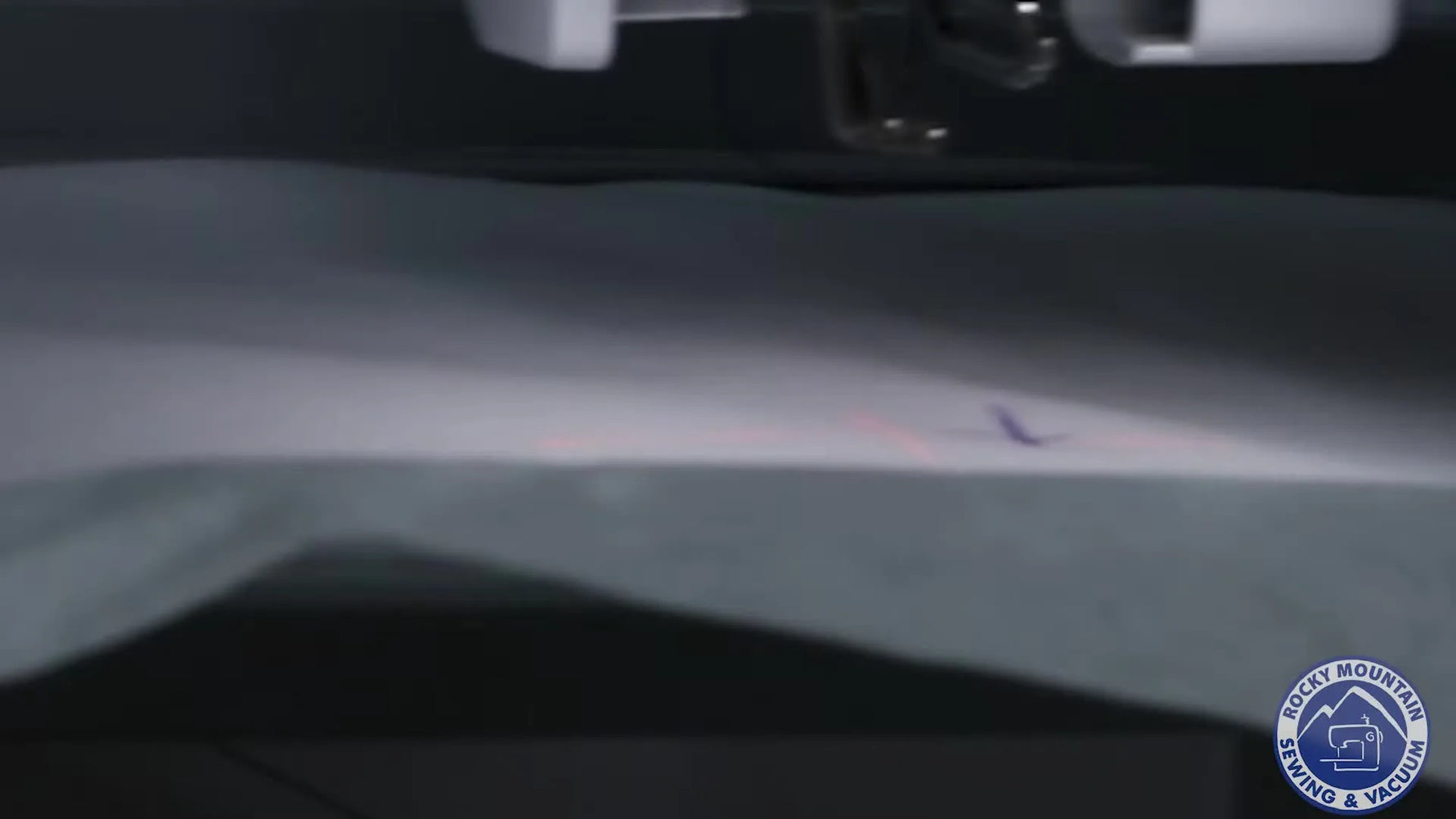 A close-up of the PR1X red laser crosshair landing precisely on marked fabric to lock in alignment before stitching.