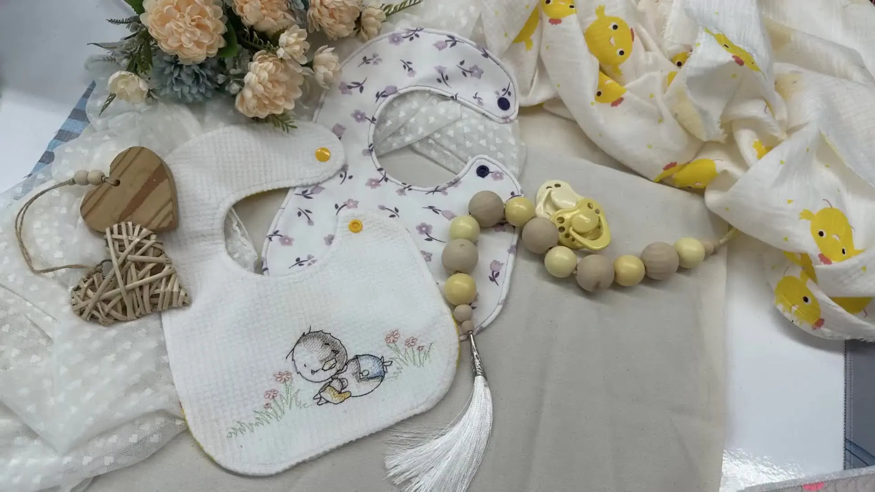 Three finished baby bibs displayed with baby accessories and flowers.