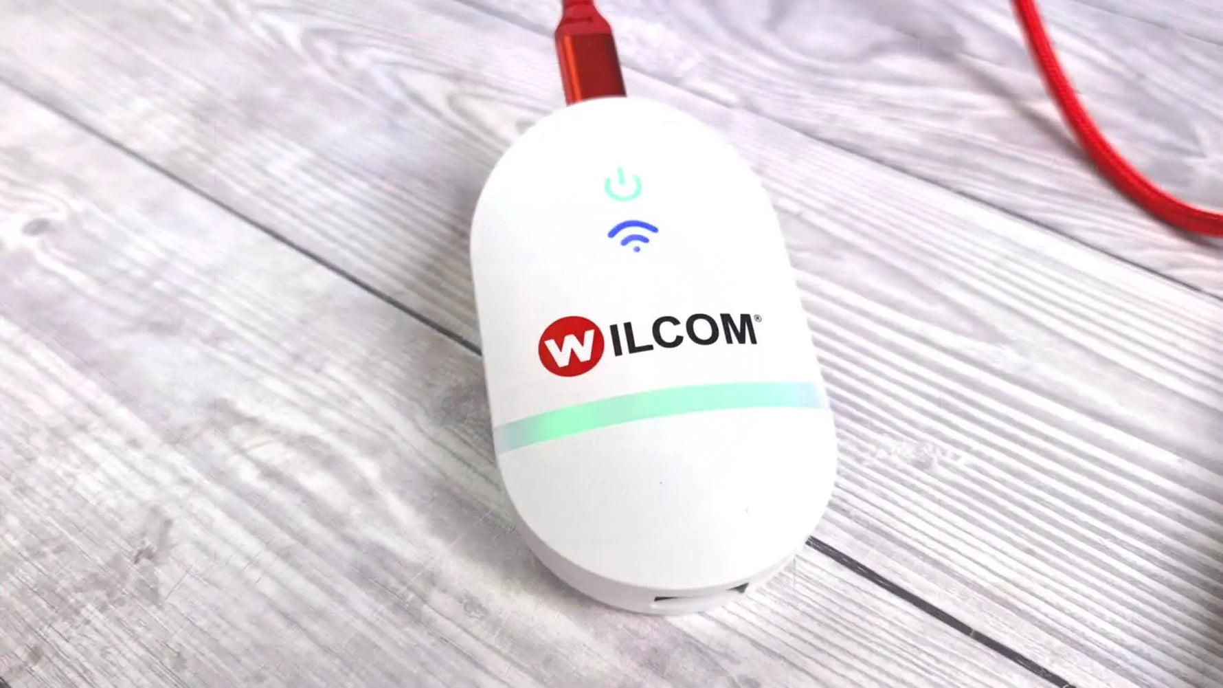 A close-up of the Embroidery Connect device on a desk with its LEDs active while it receives a design wirelessly.