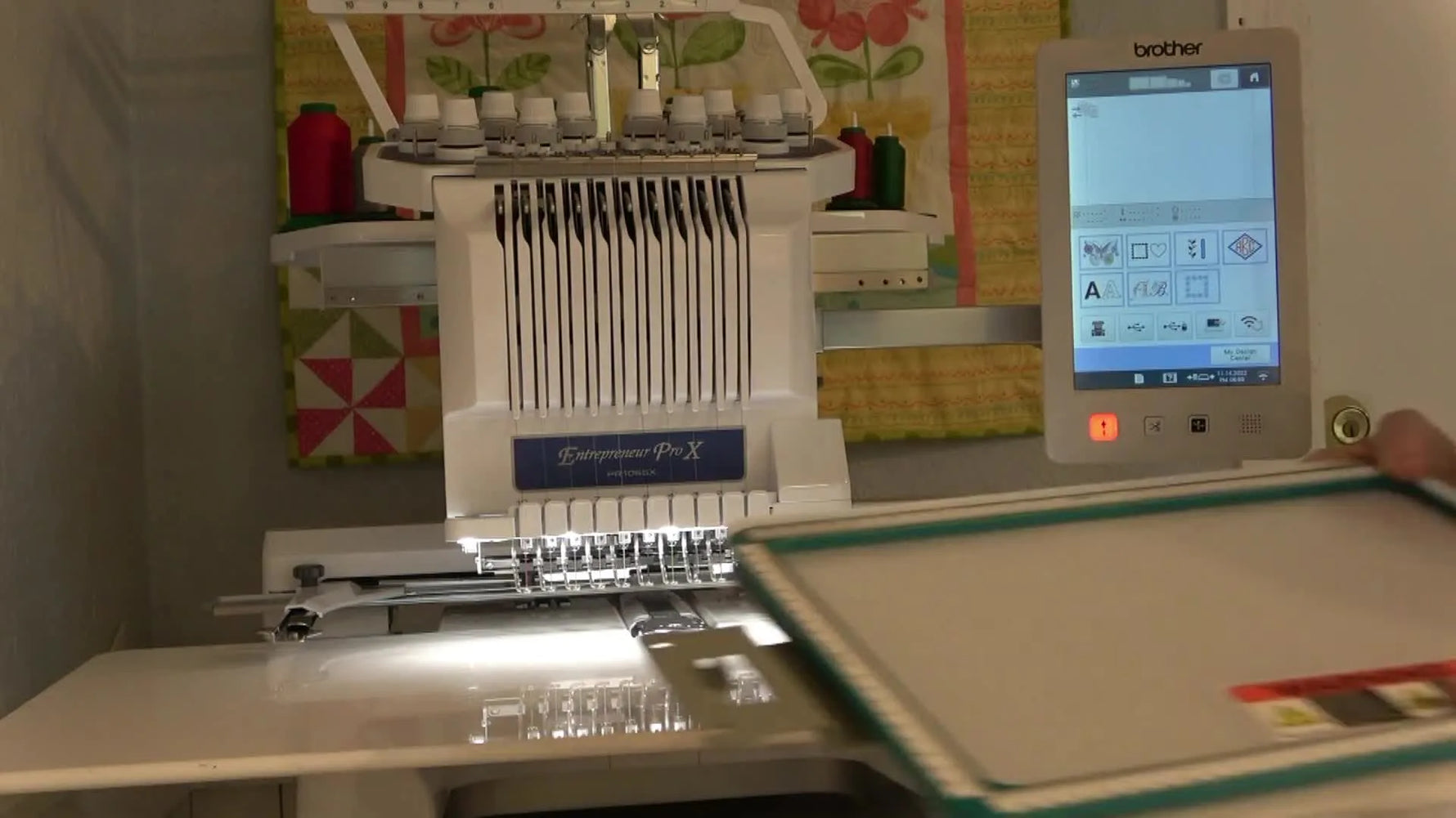 A close-up shows an 8x12 magnetic hoop being held ready to load stabilizer before stitching an appliqué quilt panel.