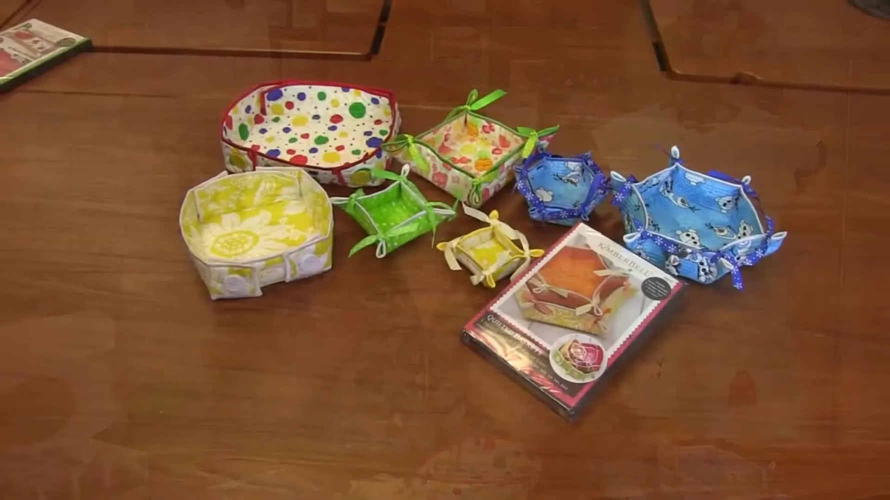 A colorful collection of quilted in-the-hoop baskets arranged together, showing multiple shapes, sizes, and quilting textures.