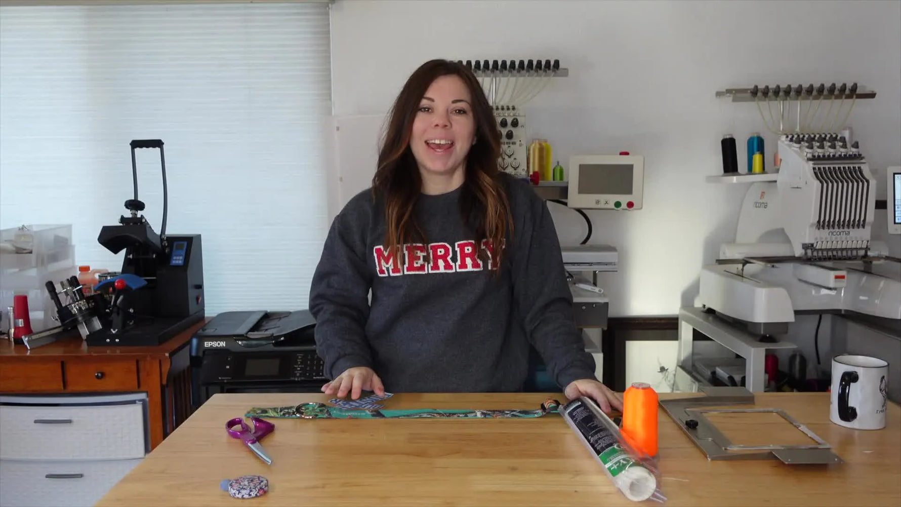 Woman holding a dog collar and embroidery supplies, smiling at the camera.