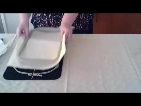 Hands press the inner hoop into the outer hoop on the grippy mat, showing stable, controlled hooping without slipping.