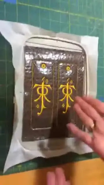 A fully stitched faux leather bookmark in the hoop shows the finished design quality before trimming, punching, and adding the tassel.