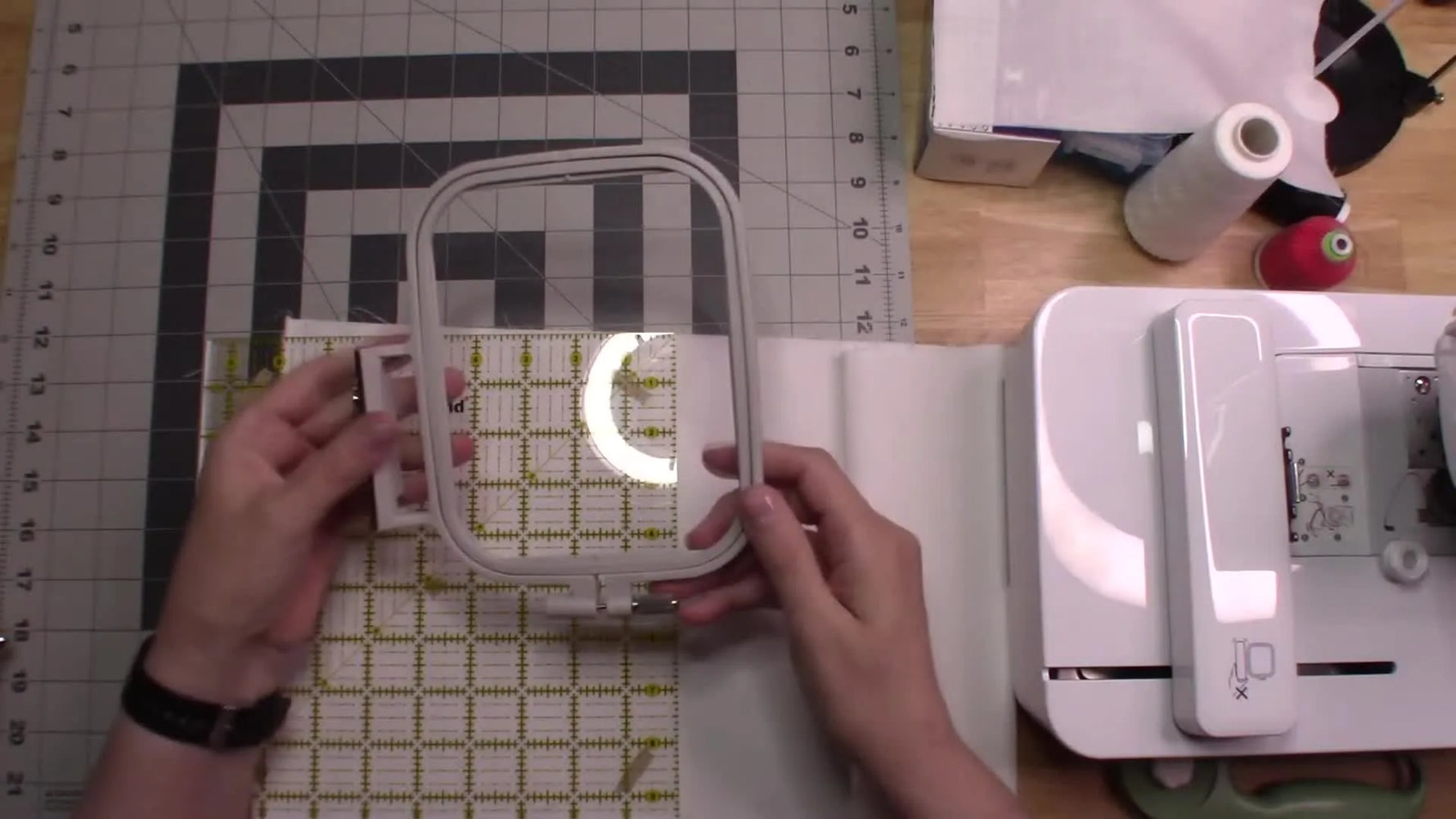 An overhead view of a Brother 4x4 hoop placed over a ruler and fabric to confirm the 8-inch cutting margin before hooping.