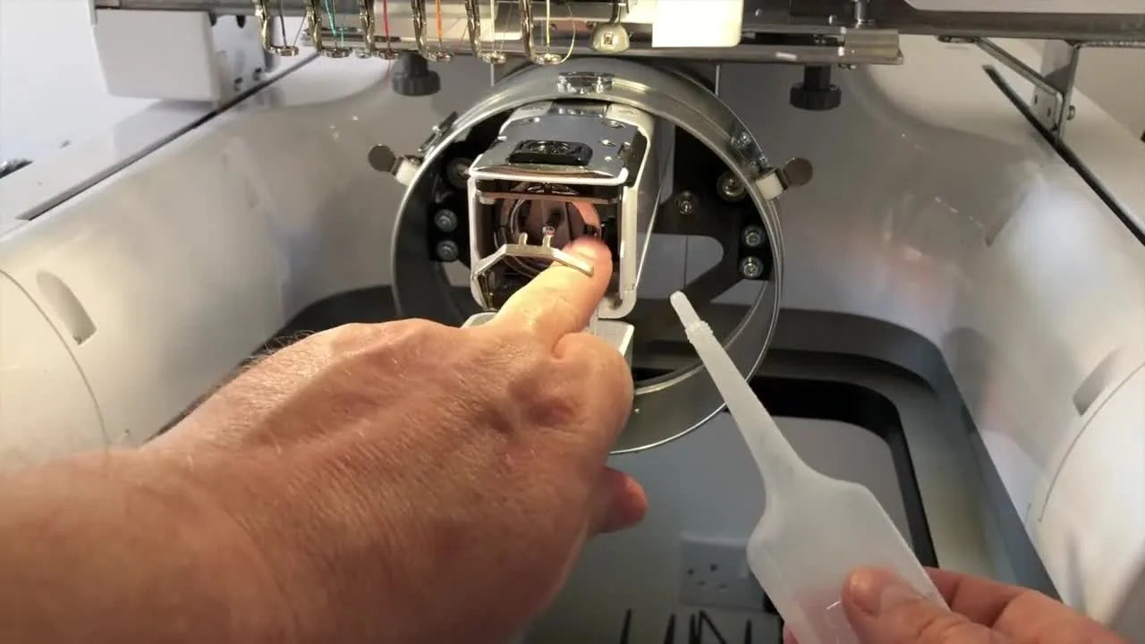 A close-up shows the precise 3 o’clock oiling point on the rotary hook race inside a Brother PR670E.