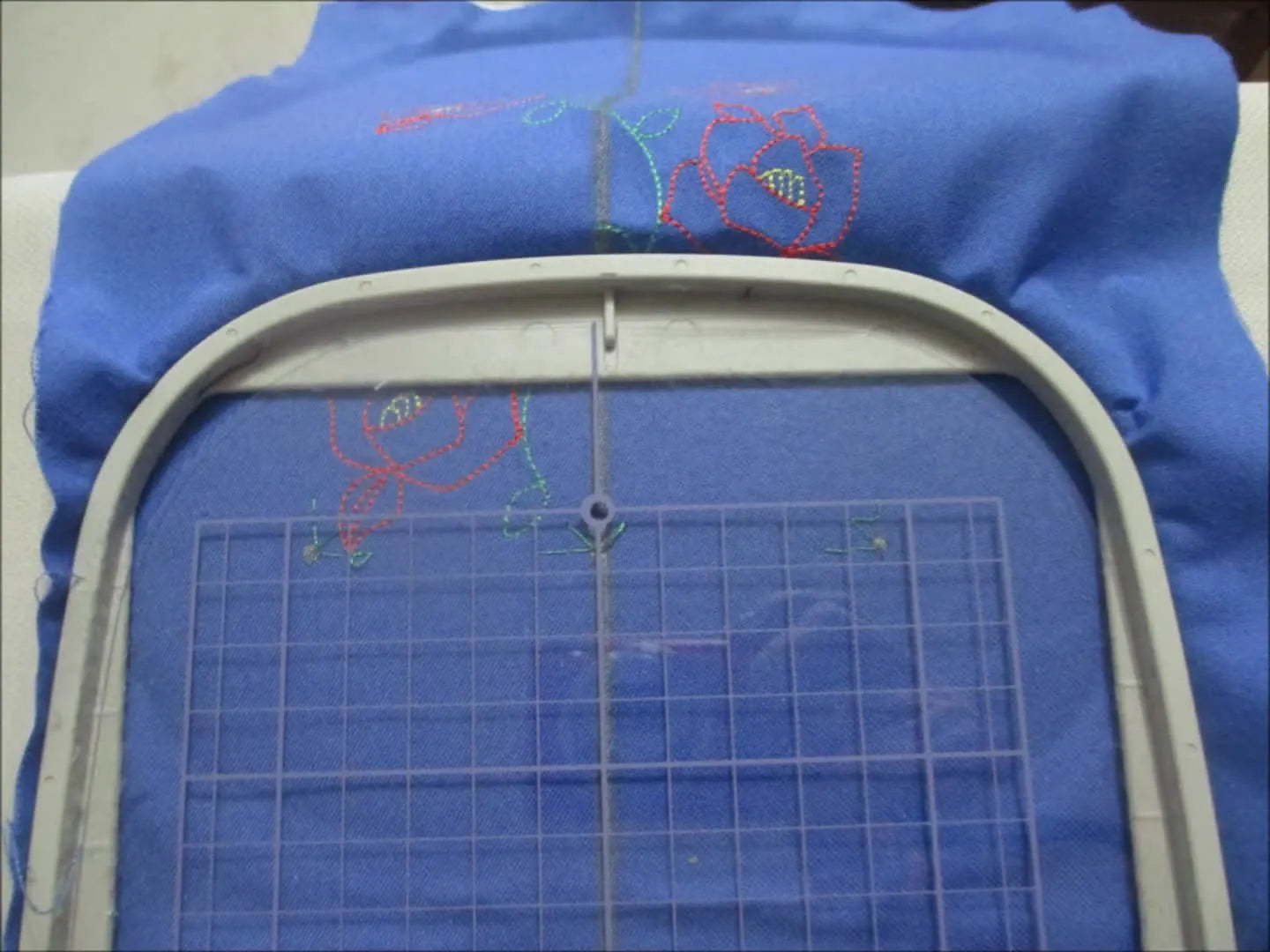 Re-hooping the fabric with the previously stitched alignment markers clearly visible inside the hoop’s sewable grid area.