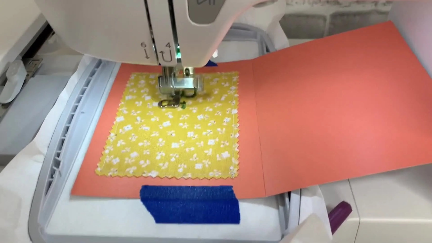 A close-up action shot of the Singer SE9180 needle stitching a letter onto cardstock using the floating technique.