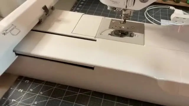 The Brother PE800 embroidery unit is being slid into the main machine body, capturing the exact alignment moment before the locking click.