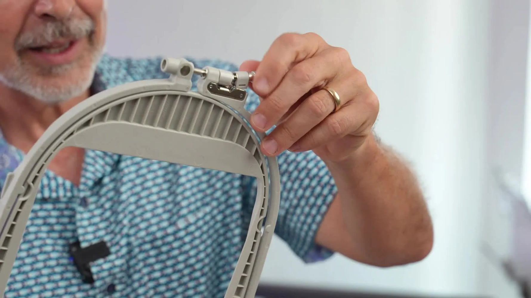 Man demonstrating how to open and adjust an embroidery hoop.