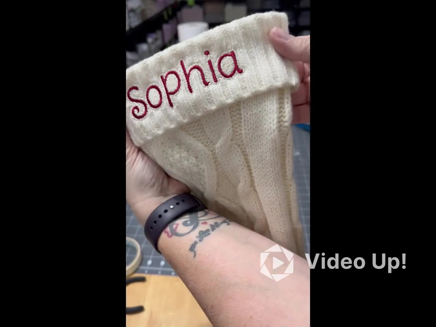 A finished cable-knit Christmas stocking is shown right-side out with a clean, centered embroidered name on the cuff.